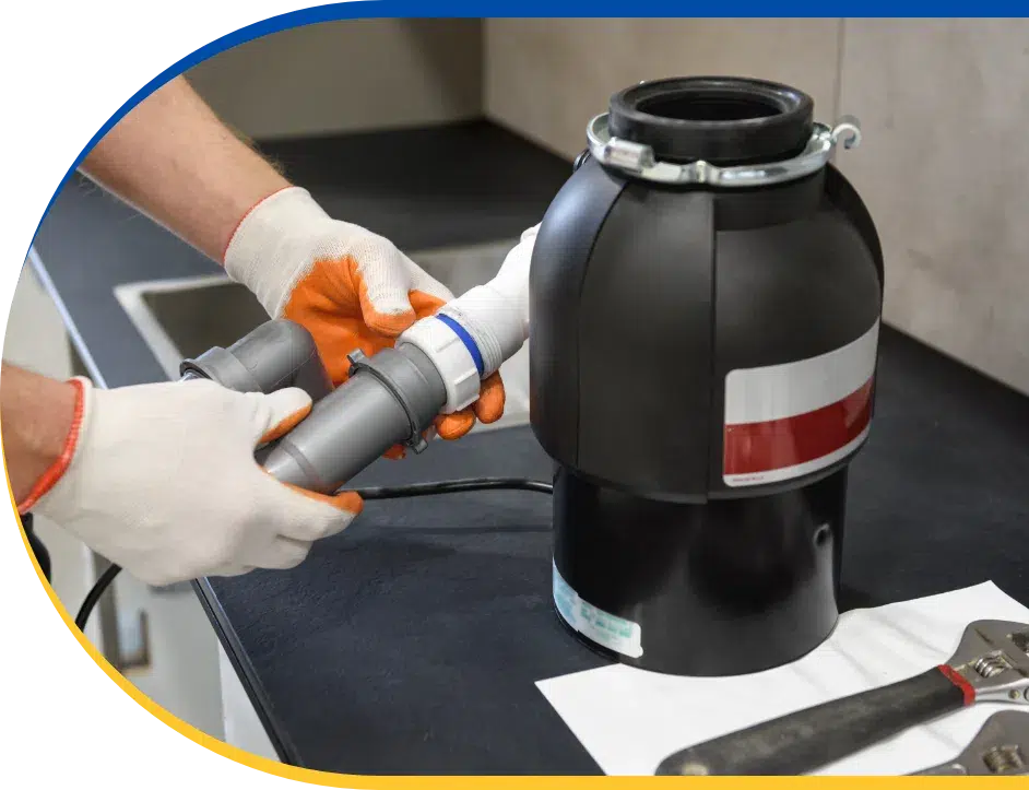 a worker servicing a garbage disposal using tools inside a kitchen